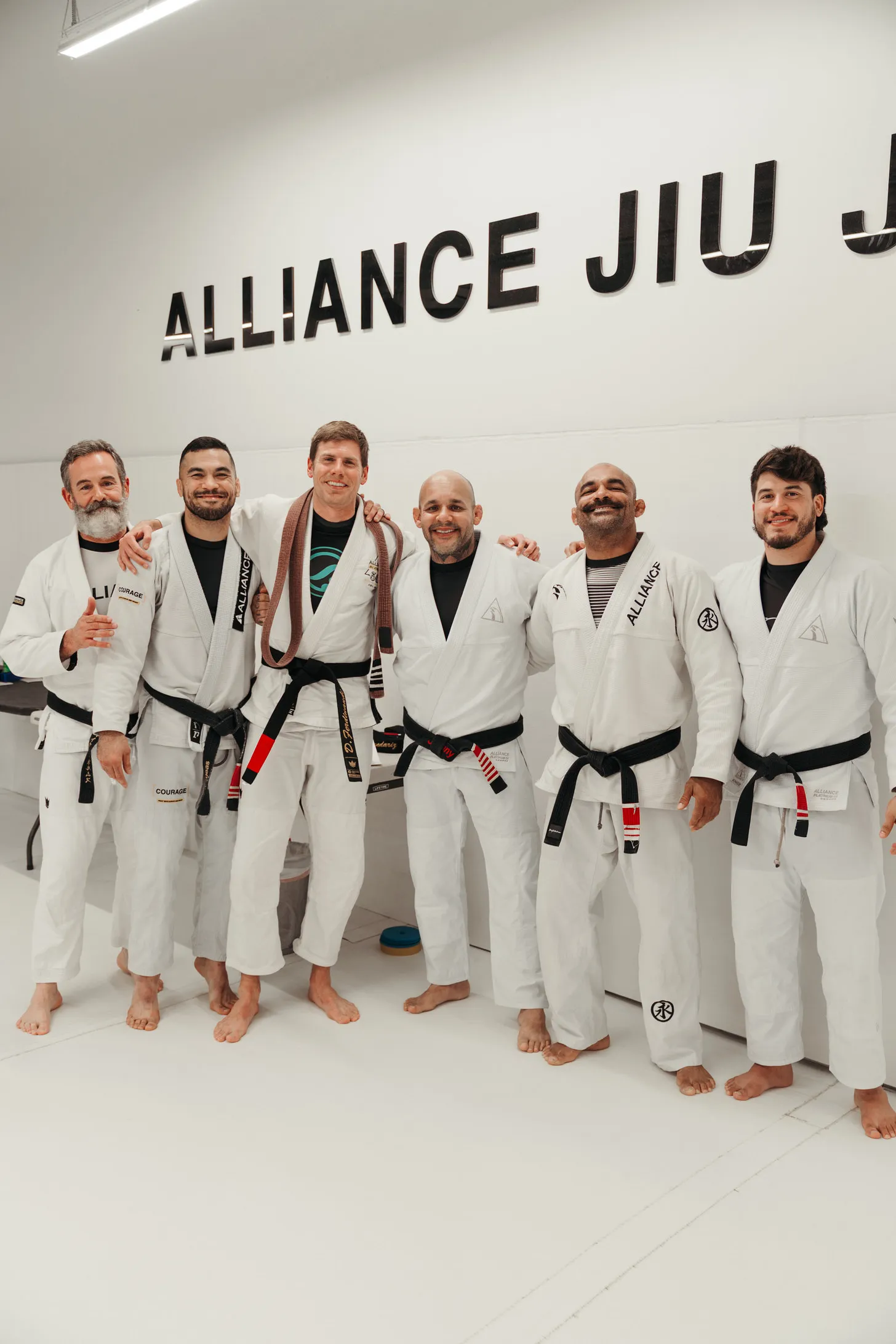 Six Brazilian Jiu-Jitsu practitioners in white gis at Alliance Jiu Jitsu.